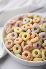 Tasty cereal rings in bowl on white table, closeup