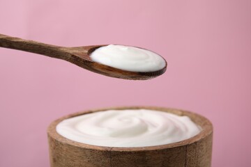 Eating delicious natural yogurt on pink background, closeup