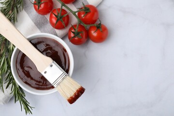 Marinade in bowl, basting brush, tomatoes and rosemary on white marble table, flat lay. Space for...