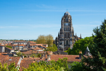 Panoramic view of historic city of Saintes known from Roman times. Charente-Maritime, France. Old city red tiled roofs drowned in greenery; cathedral at background. Architecture, environment, heritage