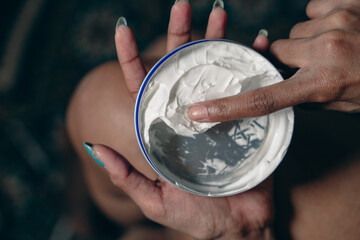 A woman is applying lotion to her hand