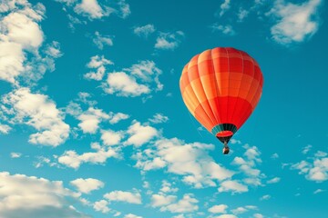 Fototapeta na wymiar A hot air balloon is flying high in the sky above a blue and cloudy sky