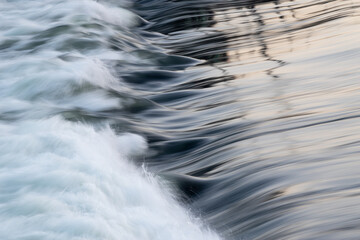 Rapid water flow over barrier with silky surface, river overflow over dam close up with splash and...