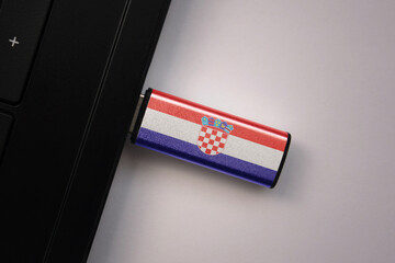 usb flash drive in notebook computer with the national flag of croatia on gray background.