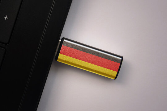 usb flash drive in notebook computer with the national flag of germany on gray background.