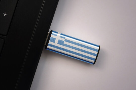 usb flash drive in notebook computer with the national flag of greece on gray background.