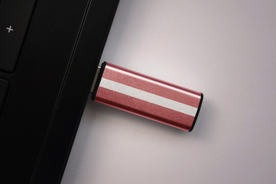 usb flash drive in notebook computer with the national flag of latvia on gray background.