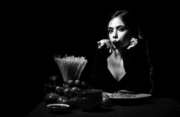 Hungry beautiful woman eat on noodles spaghetti on black background.