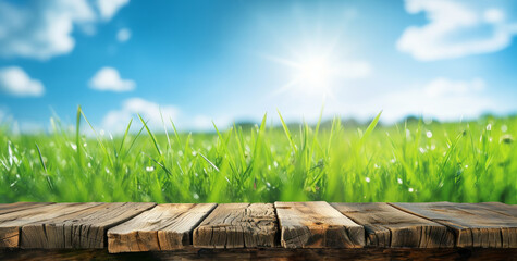 Old wooden table surface with picturesque view of green grass and blue cloudy sky, perfect for spring summer displays - 755860620
