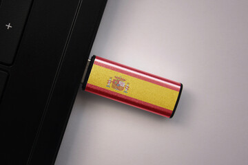 usb flash drive in notebook computer with the national flag of spain on gray background.
