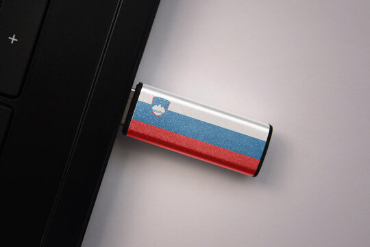 usb flash drive in notebook computer with the national flag of slovenia on gray background.