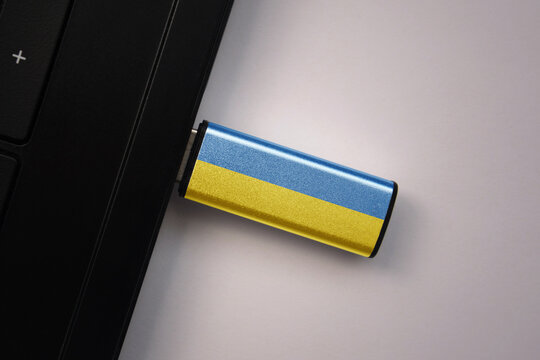 usb flash drive in notebook computer with the national flag of ukraine on gray background.