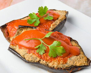 Stuffed eggplant with red sauce and parsley on a white plate, typical food, typical mediterranean mallorcan cuisine typical from balearic islands mallorca, spain