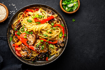 Vegan stir fry noodles with red paprika, champignons, green onion and sesame seeds with ginger,...