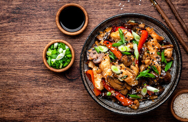 Stir fry turkey slices with red paprika, mushrooms, chives and sesame seeds with ginger, garlic and soy sauce. Old wooden table background, top view