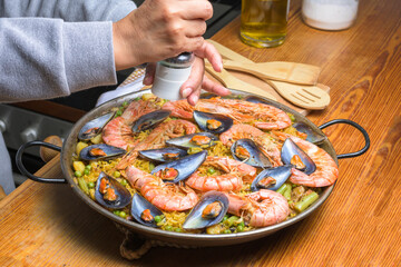 Seasoning a seafood paella with salt, a step in the cooking process of this flavorful Spanish meal, typical Spanish cuisine, Majorca, Balearic Islands, Spain