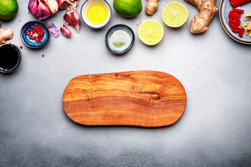 Food and cooking background with fresh raw vegetables. Wooden cutting board, paprika, zucchini, spices and ingredients for cooking Asian dishes with ginger, garlic, soy sauce and lime, top view