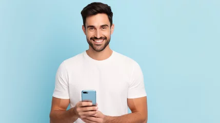 Foto auf Acrylglas Young man smiling and holding his smartphone on a colored background © MP Studio