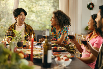 Happy people enjoying in conversation and drinking wine during festive dinner at home party