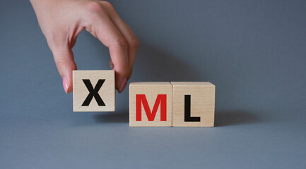 XML - Extensible Markup Language. Wooden cubes with word XML. Businessman hand. Beautiful grey background. Business and Extensible Markup Language concept. Copy space.