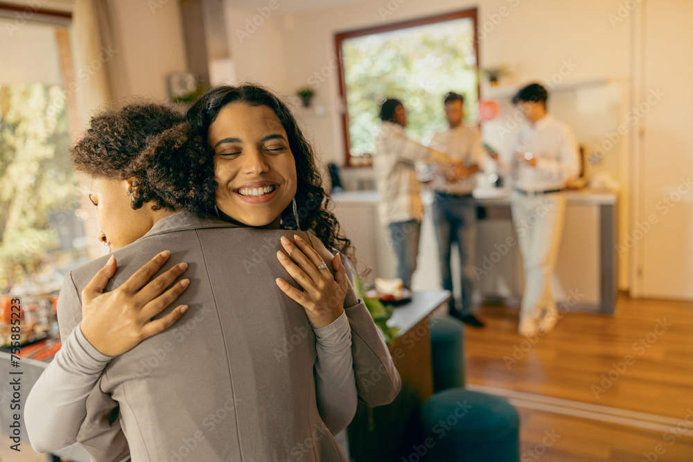 Wall mural smiling female friends hugging and enjoy time spent together on holiday home party