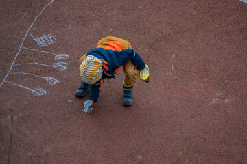 Kind spielt auf dem Spielplatz mit Kreide