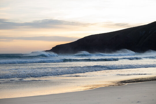 sunset at sandfly bay in new zealand in spring with wind and waves