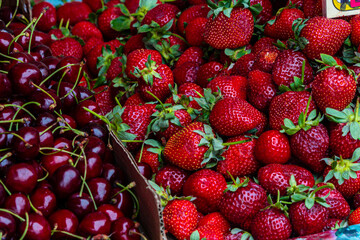 A scattering of strawberries and cherries in close-up at the farmer's market. Sale of berries