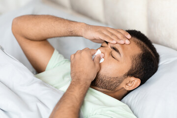 Fototapeta na wymiar Sick african american man lying in bed, got flu