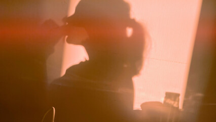 Silhouette of girl drinking coffee in the morning. Shadow of woman enjoying breakfast. Film grain texture. Soft focus. Blur