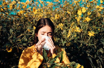 Pollen allergy concept. Young woman is going to sneeze. Closeup portrait of sneezing girl at yellow...