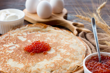 Maslenitsa holiday, pancakes with red caviar and sour cream on the table. The Russian tradition