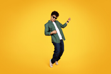 Cool african american guy playing invisible guitar, yellow background - obrazy, fototapety, plakaty