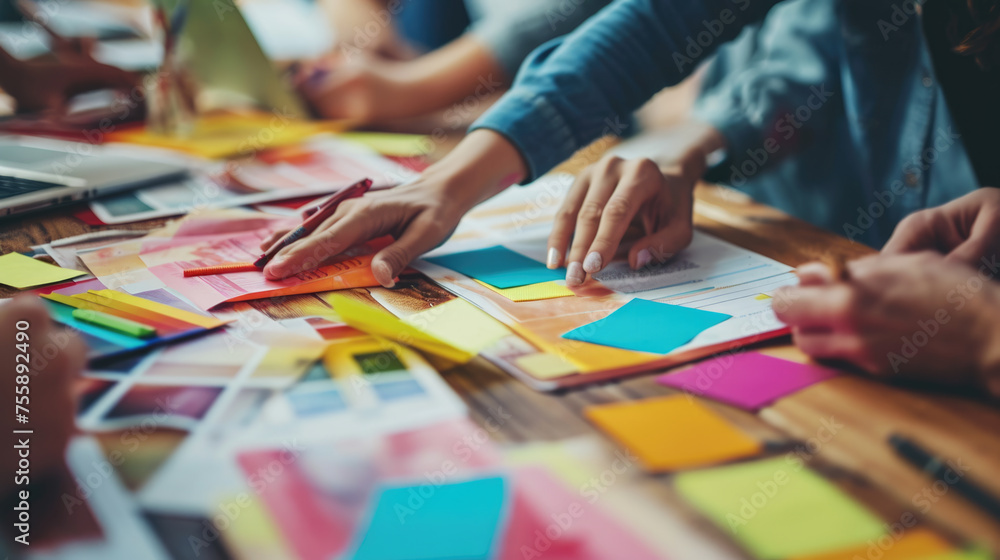 Poster ?lose-up view of several hands collaboratively working on a project with colorful sticky notes, pape