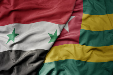 big waving national colorful flag of togo and national flag of syria .