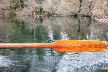 Closeup of oar paddle from row boat moving in water on green lake with ripples - 755896099