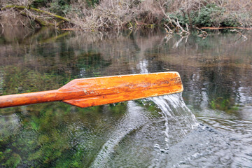 Closeup of oar paddle from row boat moving in water on green lake with ripples - 755896299