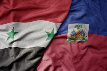 big waving national colorful flag of haiti and national flag of syria .