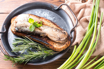 a sandwich with sprats. Fried black bread with smoked fish in oil