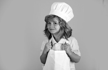Chef kid boy making fresh vegetables for healthy eat. Portrait of little child in form of cook...