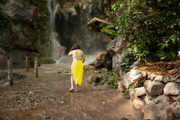 Woman enjoying the cool breeze next to the fresh water waterfall natural environment moss rocks and water in Hidalgo, State of Mexico.
