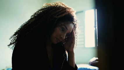 One preoccupied middle-aged black woman feeling anxiety and worry by bedside contemplation....