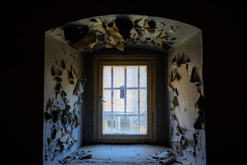 Blick nach draußen durch ein vergittertes Fenster aus einem kalten dunkeln Raum heraus