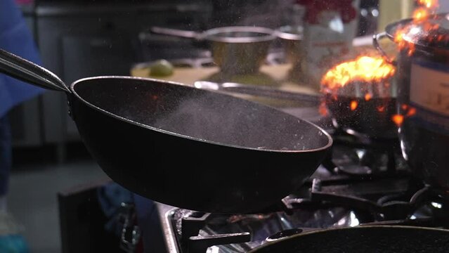 Chef's hands toss food on carpet, which turns into flames and ignites from fire in slow motion. Close-up of chef's hands cooking food on fire. Chef in professional kitchen.