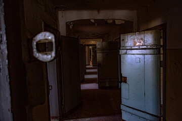 Langer dunkler, düsterer Gang in einem alten Gefängnis.
Alle Zellentüren stehen offen.