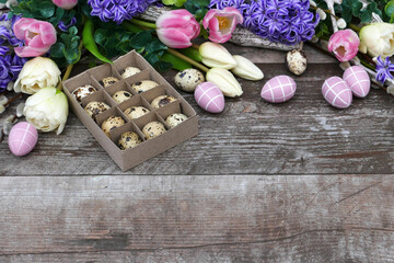 	Osterhintergrund: Harmonische Osterdekoration mit Blumen und Ostereiern auf schäbigem Holzbrett mit Platz für Text.