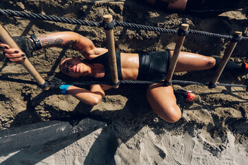 High angle shot of a woman crawling under the ladder during an OCR race