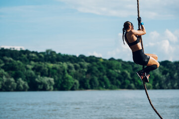Strong woman climbing a rope while participating in an obstacle course race