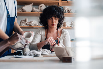 Pottery class attendee with clay in hands learning clay work with tutor