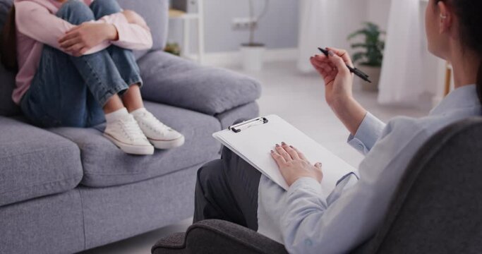 Psychologist consulting a teenage girl in a therapy session, offering support and guidance for mental health. The compassionate interaction helps the girl feel understood and supported.